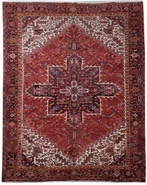 Brick red Persian Heriz rug with ivory corner spandrels and navy blue geometric star medallion