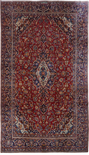 Full view of red Persian Kashan rug with ivory medallion and deep navy floral border