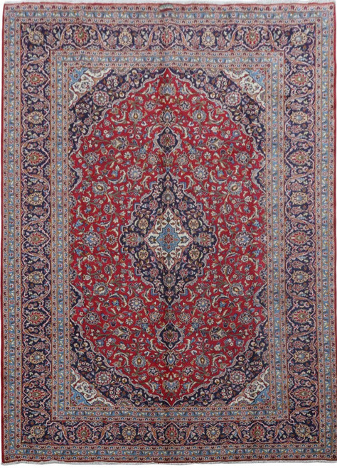 Full view of red Persian Kashan rug with navy floral borders and ivory center medallion