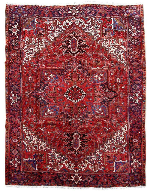 Full overhead view of red Persian Heriz rug with ivory spandrels, navy border, geometric medallion