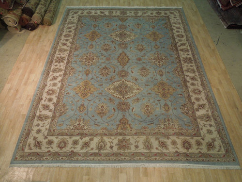 Teal blue Oushak design rug with ivory floral border displayed flat on light hardwood showroom floor