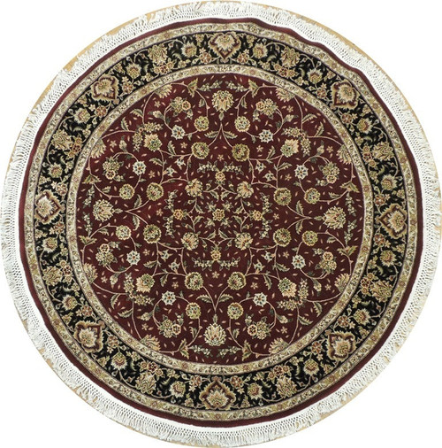 Round red Oriental rug with black floral border and ivory fringe photographed from directly above
