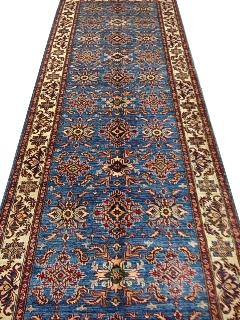 Long blue Kazak runner rug with ivory border and repeating red geometric medallions, full length view