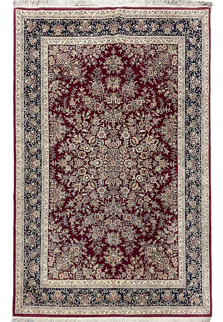 Full overhead view of the burgundy Tabriz rug with dark navy border and ivory fringe at both ends