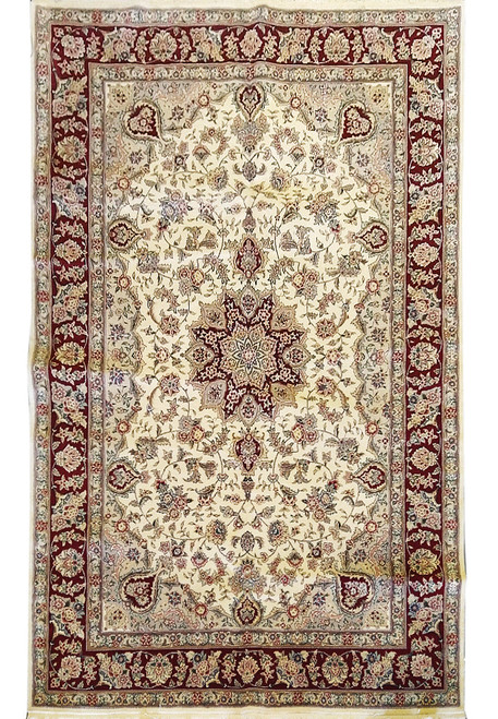 Full overhead view of the ivory Tabriz-design rug with burgundy borders and central star medallion