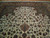 Angled floor view showing ivory field, rust cartouche, scrolling vines and paisley filled inner border