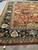 Angled corner view showing multi-band border, olive gold shield motifs and deep rust field