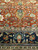 Symmetrical navy cartouche and sage leaf cluster centered above the indigo border, detailed weave view