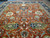 14' x 22'2" hand-knotted rug viewed lengthwise, rust field framed by a navy floral border
