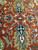 Close view of navy palmettes, olive leaves and salmon rosettes woven on a rust background