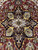 Black stepped star medallion with gold serrated leaf blades on deep burgundy red field