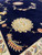 Floor-level view of cream and salmon rosette on midnight blue wool and silk Tabriz pile