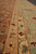 Honey gold guard border with scrolling vine beside the sage green main border of the rug