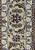 Taupe main border of a Persian Isfahan rug with navy and red palmettes, flower clusters and ivory guards