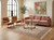 Styled living room with pink sofa, leather chairs and a floral rug under a glass coffee table