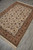 Angled floor view of the rug on grey tile, border and ivory field seen in perspective