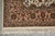 Corner detail with the tan border meeting the ivory field above the knotted ivory fringe