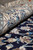 Rolled edge of the rug showing ivory border pile beside the navy field at floor level