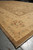 Angled end view of the carpet with the gold border, olive outer band and fringe in focus