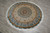 The round rug lying on a grey tiled floor, photographed from above at a slight angle