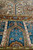 Angled detail of blue arcaded panels, ivory pearl outlines and the brown floral border band