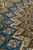 Detail of small blue and caramel compartments meeting the brown band of four-petal flowers