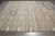 Rug seen lengthwise on grey tile, ivory lattice field with a charcoal panel at the far corner