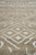 Raking close-up of knotted wool, rows of ivory diamonds over flecked beige yarn