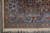 Corner photographed from above: blue border with boteh and vases, camel guard band, fringe