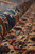 Rolled edge in close focus where the blue border turns against the beige Herati field