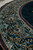 Angled close-up of the curving border scrollwork with lavender guard stripe alongside