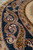 Angled close-up of the indigo main border, large ivory and gold botehs outlined in fine burgundy