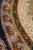 Detail of the slate-green guard band, gold scroll line and ivory field tracery at a low angle