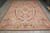Rug laid on a grey floor, photographed from one end, full oval centre and corner baskets visible