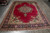 Whole rug flat on grey tile floor, open red field and wide navy border