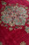 Diagonal close view of the medallion and its pendant against the deep red open field