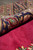 Rolled edge of the rug showing pile depth, border colours and the flat reverse