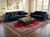 Rug laid under a wooden coffee table between two navy velvet sofas in daylight