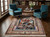 Rug staged in a wood-panelled library between two teal velvet armchairs and a small round table