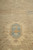 Raking-light detail of a soft blue medallion sitting in the sand-coloured wool pile