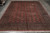 Whole rug laid flat on grey tiled floor, photographed from one end showing the full border layout