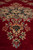 Low-angle detail of the medallion and pendant, pile catching light across the red field