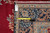 Edge of the rug with a tape measure across the navy border and inventory tag