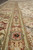 Border close-up showing sage green guard stripe, terracotta rosettes and fine knot definition