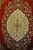 Close-up of the cream and gold central medallion ringed by delicate floral sprays on red