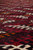 Low angle macro of dense wool pile showing burgundy, black and rust tribal lattice detail