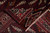 Folded corner revealing the rug back and tight hand-knotted weave beside pale pink fringe