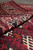 Rolled edge showing pile depth, saturated burgundy wool and crisp ivory geometric border detail