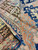 Folded corner revealing the reverse, dark brown border band and rose secondary stripe in wool