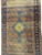 Rust and navy antique Tabriz design rug upright, showing medallion, pendants and wide floral border